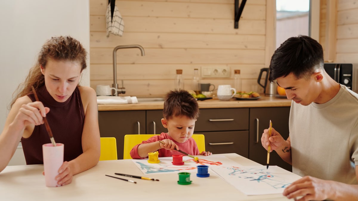 A family enjoying creative painting time together in a cozy kitchen setting.
